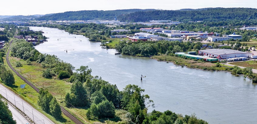 Flygfoto över del av Göta älv med motorväg och järnvägsspår till vänster om älven.