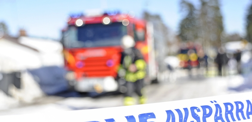Difus brandbild och brandmann i bakgrunden till en polisavspärrning.